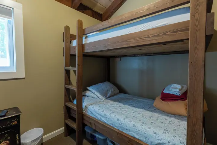 A bunk bed with a ladder, a small desk, and a window