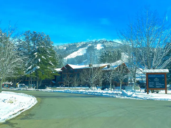 A lodge with a sign indicating amenities such as a hotel, base area, mountain park, and adventure park