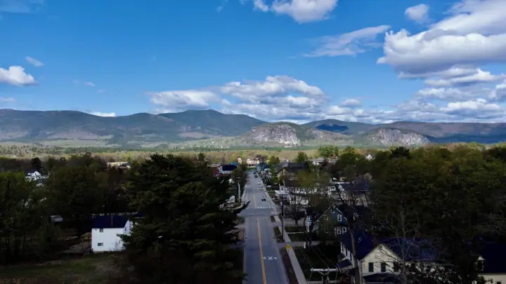 A town with a main road, houses, and mountains in the background