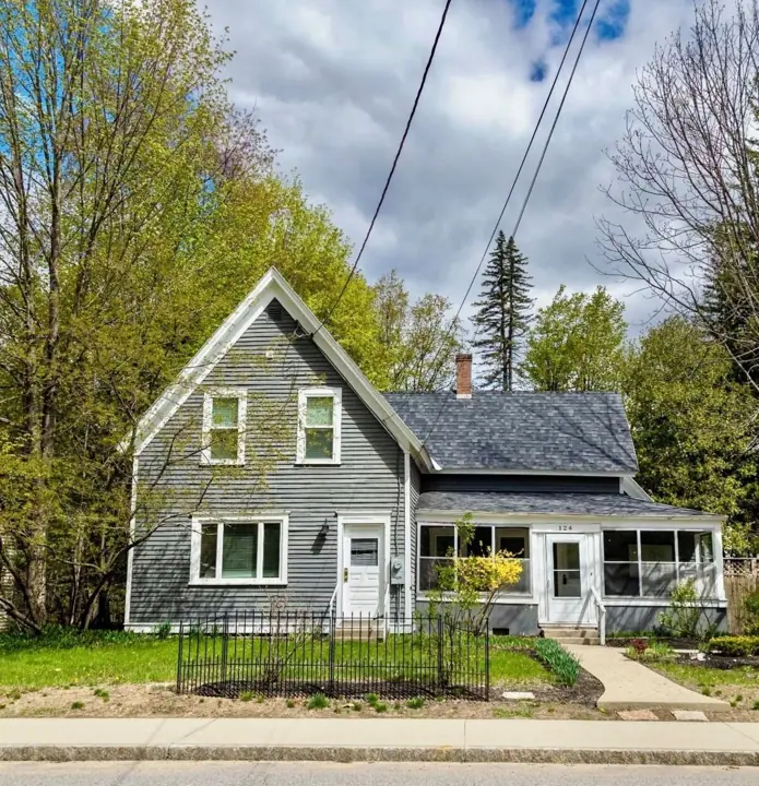 A two-story house with a gabled roof, a front porch, and a fenced yard
