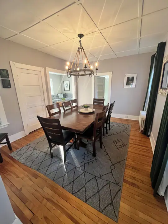 A dining room with a wooden table, chairs, and a chandelier
