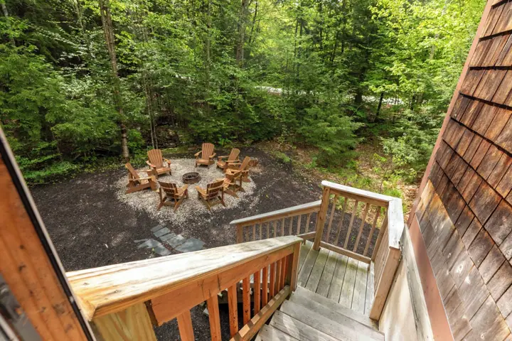 A deck with wooden railings overlooking a forested area with outdoor seating