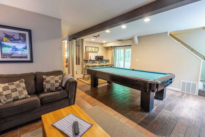A pool table, a sofa, a bar area, and a staircase