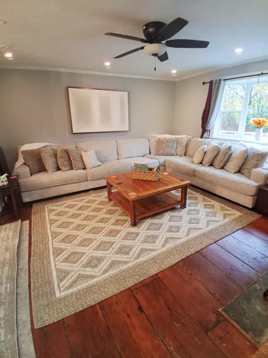 A living room with a sectional sofa, a wooden coffee table, and a patterned rug