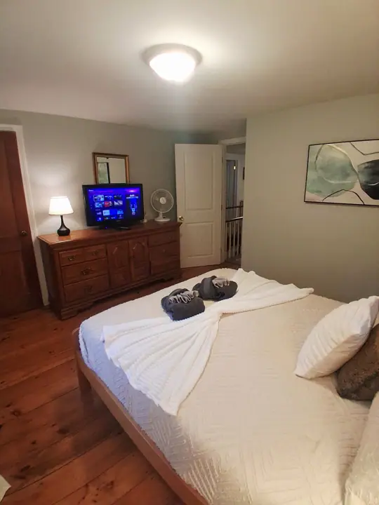 A bedroom with a bed, a dresser, a television, and a door