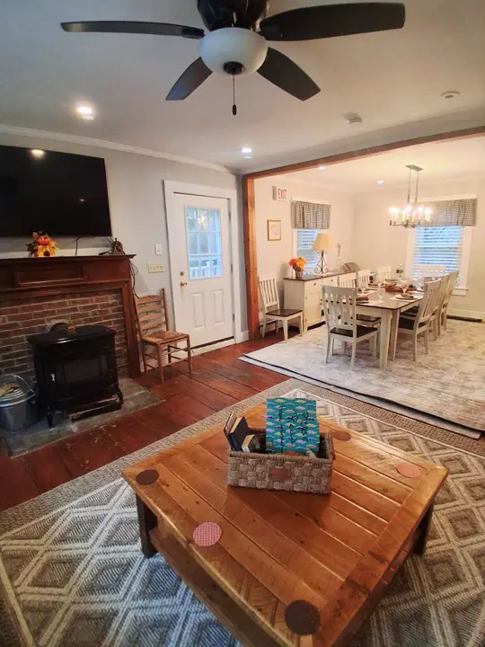 A living room with a fireplace, a dining area with a chandelier, and a ceiling fan