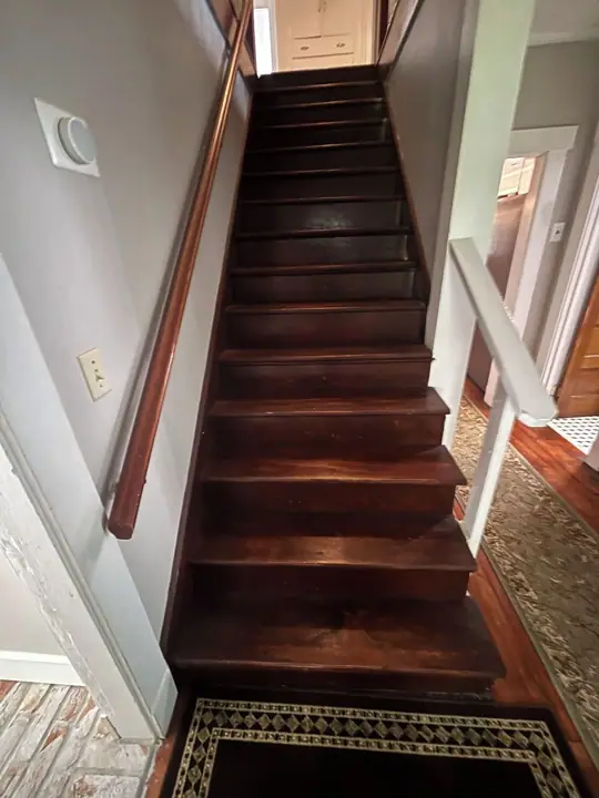 A wooden staircase with a handrail, leading to a door at the top