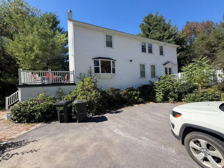 A two-story white house with a front porch, a garage, and a driveway