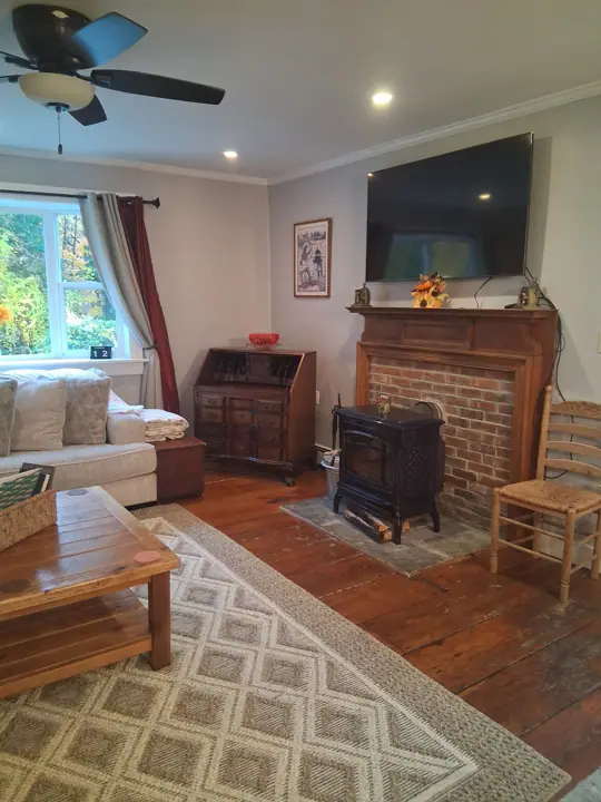 A cozy living room with a fireplace, a sofa, a coffee table, and a television mounted on the wall