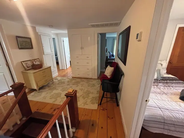 A room with a wooden staircase, a bed, a desk, and a chair