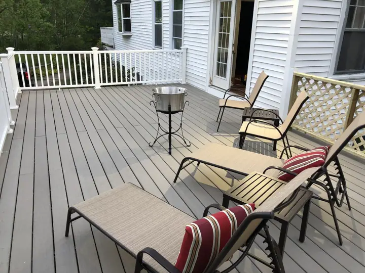 A wooden deck with outdoor furniture, including a table and chairs, and a barbecue grill