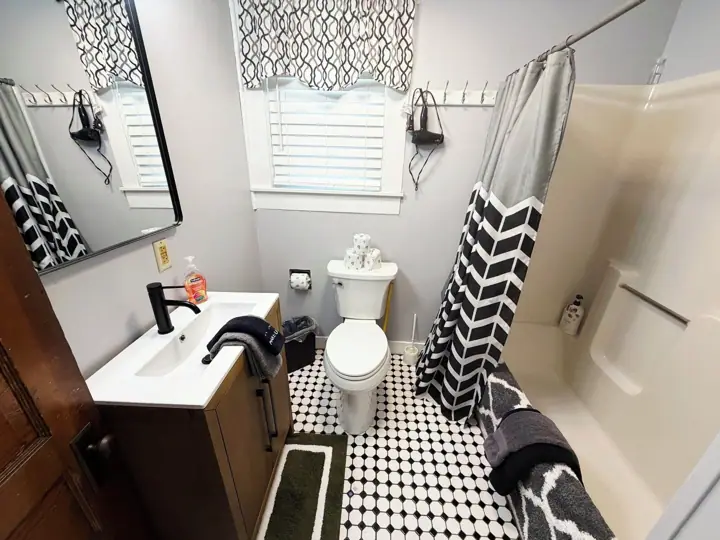 A bathroom with a white sink, black faucet, toilet, and a shower curtain with a chevron pattern