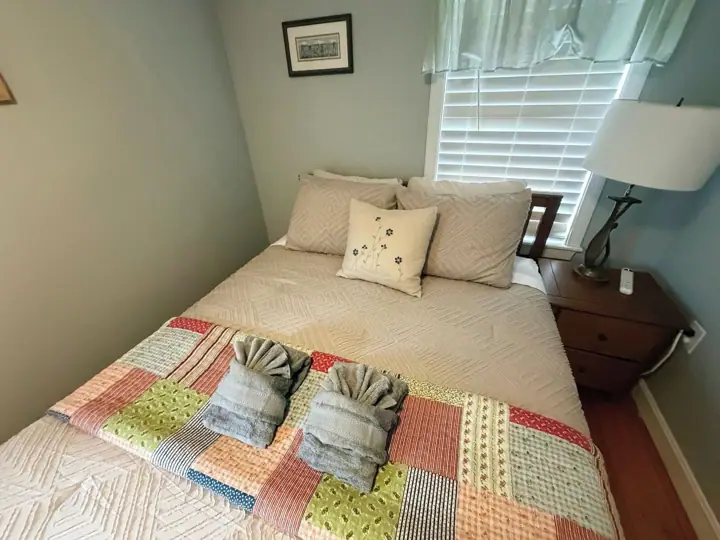 A neatly made bed with a patterned bedspread and a quilt with various colors and textures