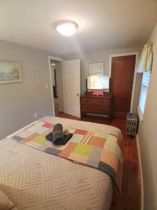 A bedroom with a bed, a dresser, a mirror, and a door