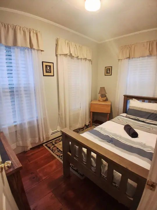 A bedroom with a wooden bed, a nightstand, and a small table with a lamp