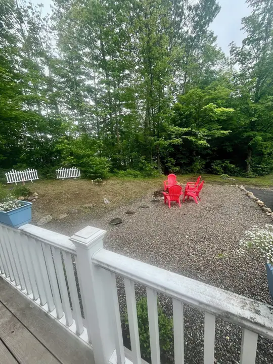 A gravel patio with red chairs and a white fence
