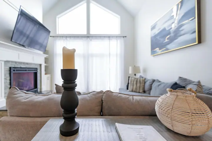 A living room with a fireplace, a television, a sofa, a candle, and a woven basket