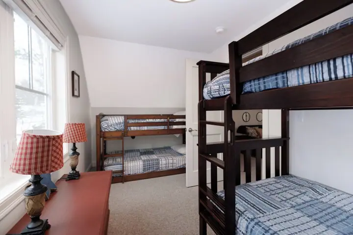 A room with bunk beds, a wooden desk, and a window