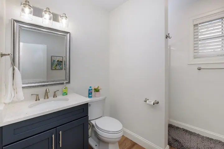 A bathroom with a white sink, a large mirror, a toilet, and a shower area