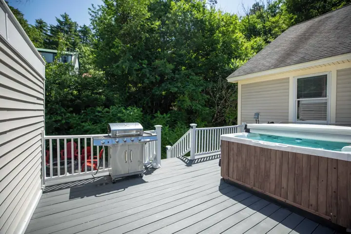A deck with a hot tub, a grill, and a pool