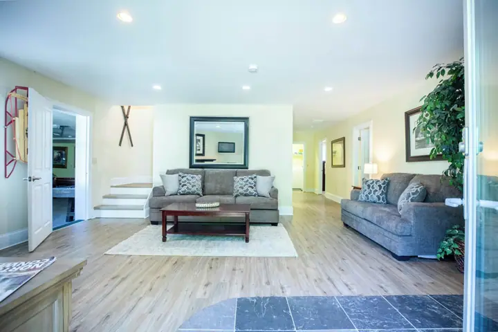 A spacious living room with a sofa, coffee table, and a large mirror on the wall