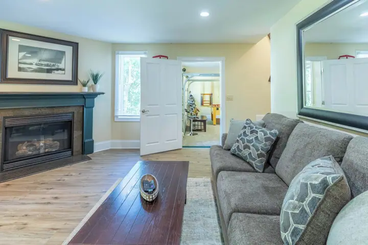 A living room with a fireplace, a sofa, a coffee table, and a door leading to another room