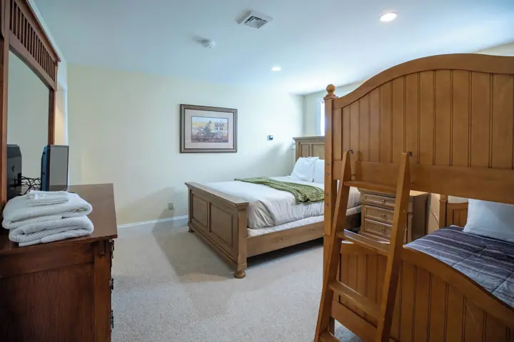 A bedroom with a wooden bed, a dresser, a framed picture on the wall, and a window