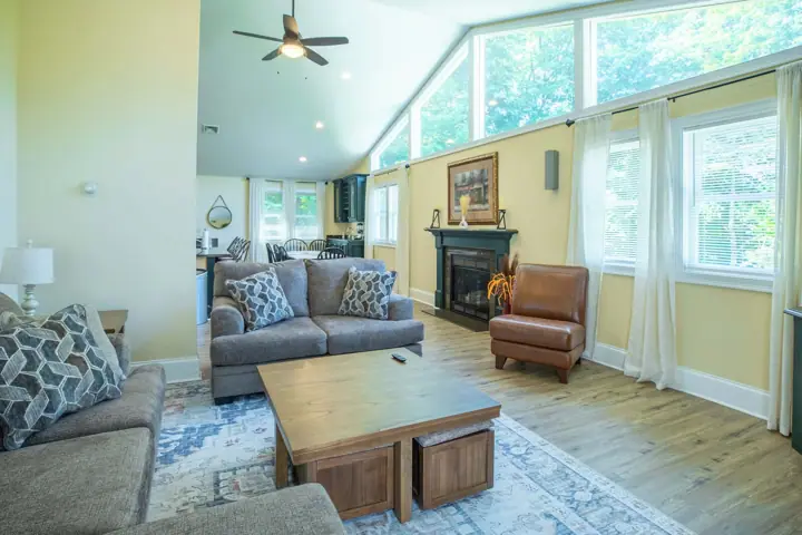 A spacious living room with a sofa, armchair, coffee table, and fireplace
