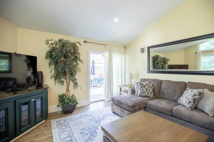 A living room with a television, sofa, coffee table, and a large mirror
