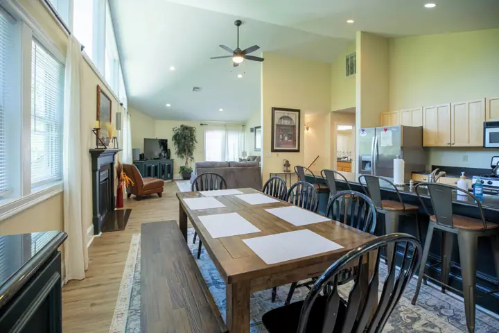 A spacious living area with a dining table, chairs, a fireplace, and a kitchen area with modern appliances