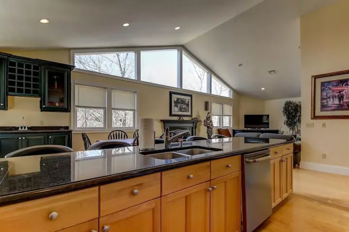 A spacious kitchen with a large island, wooden cabinets, and a view of the outdoors through large windows