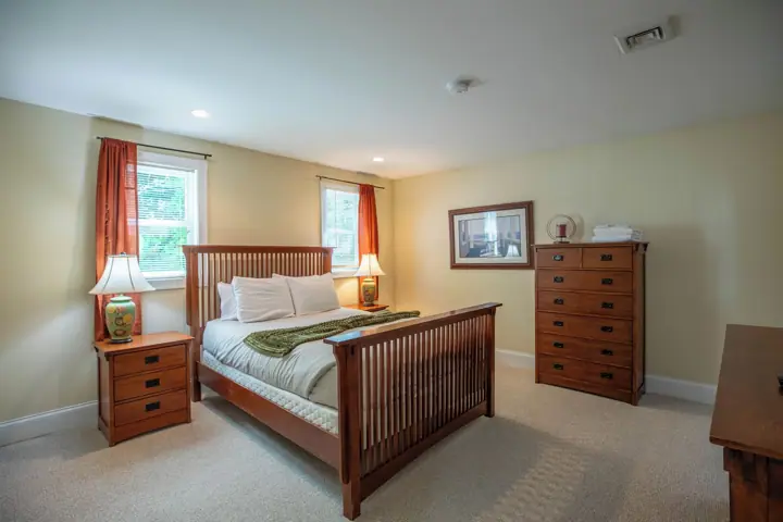 A bedroom with a bed, nightstands, a dresser, and a framed picture on the wall