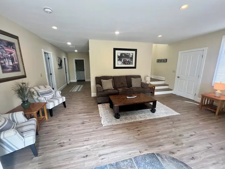 A spacious living room with a brown sofa, striped armchairs, a coffee table, and a rug