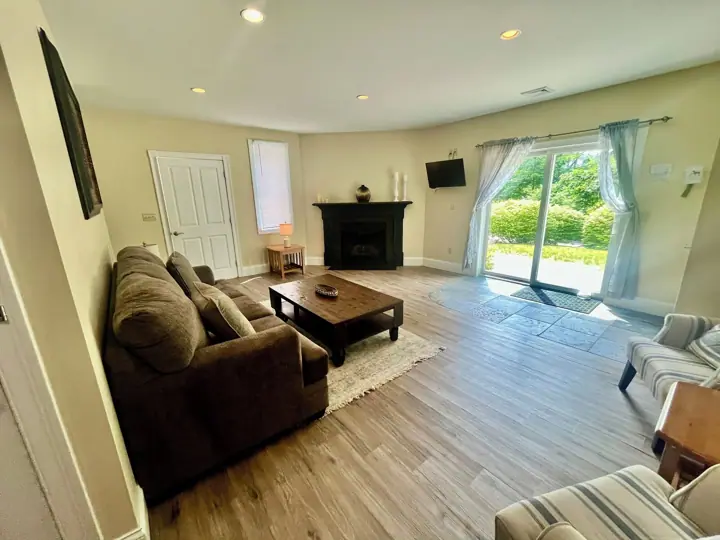 A living room with a sofa, coffee table, fireplace, and a view of the outdoors