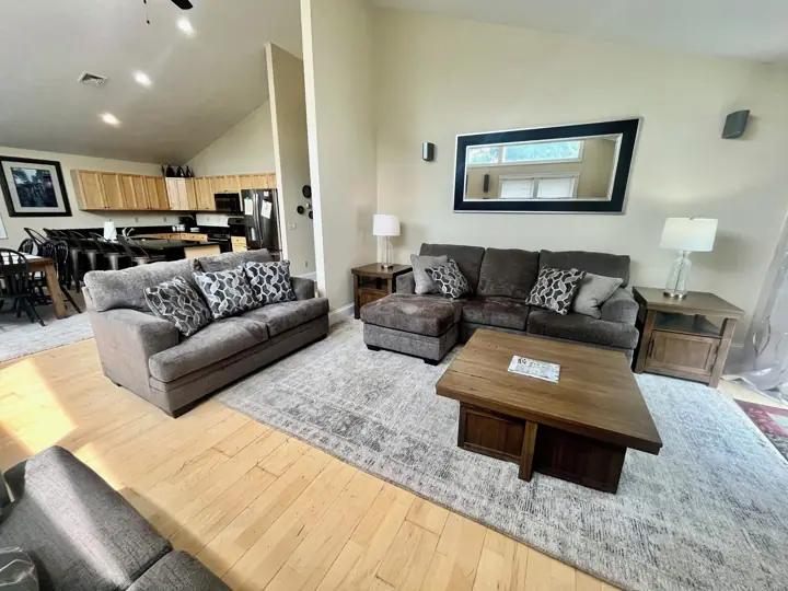A living room with a sofa, ottoman, coffee table, and a dining area with chairs and a table